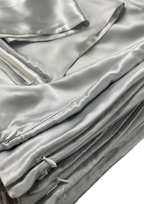 Close-up of silver silk fabric with folds, zippers